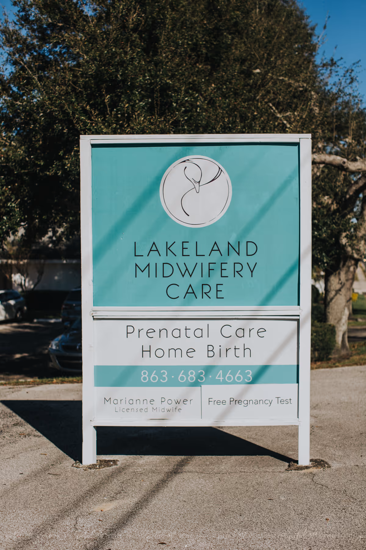 Outdoor teal signboard for Lakeland Midwifery Care advertising prenatal care and home birth