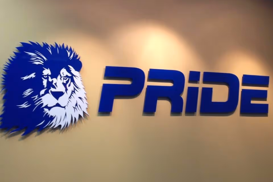 Blue lion logo and Pride sign on a beige indoor wall.