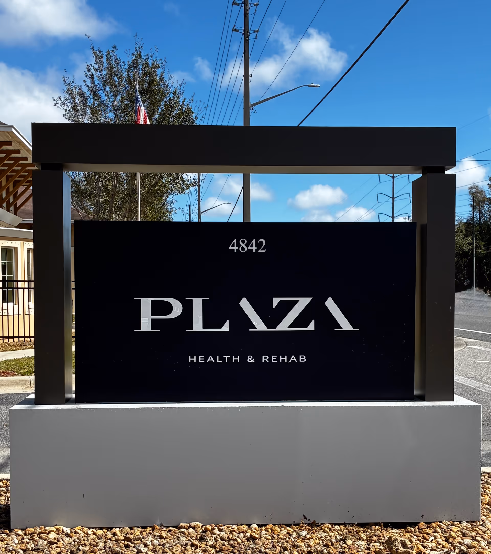 Exterior sign for Plaza Health and Rehab, address 4842, in front of the building.
