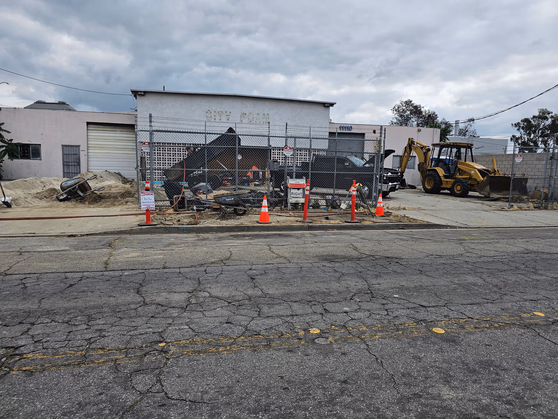 Construction site in front of Ivy Terrace building, with chain-link fence, dirt piles, and heavy equipment.