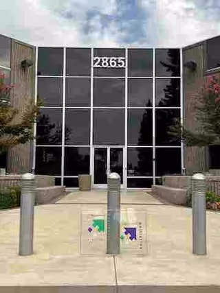 Front view of a modern building entrance with large glass windows and the address 2865.