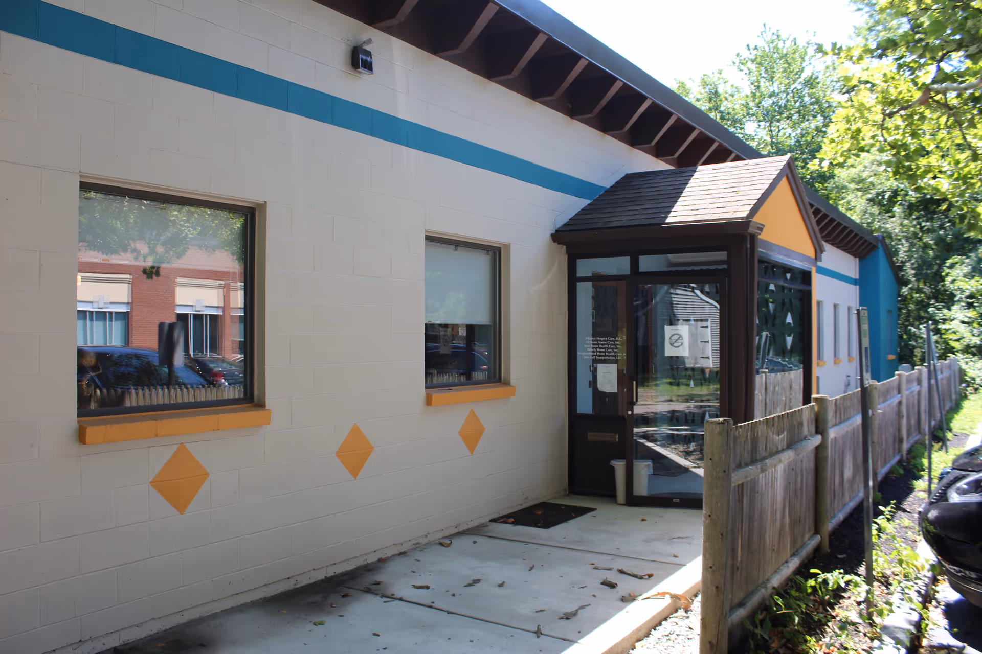 Exterior view of a facility with a glass door entrance and a wooden fence.