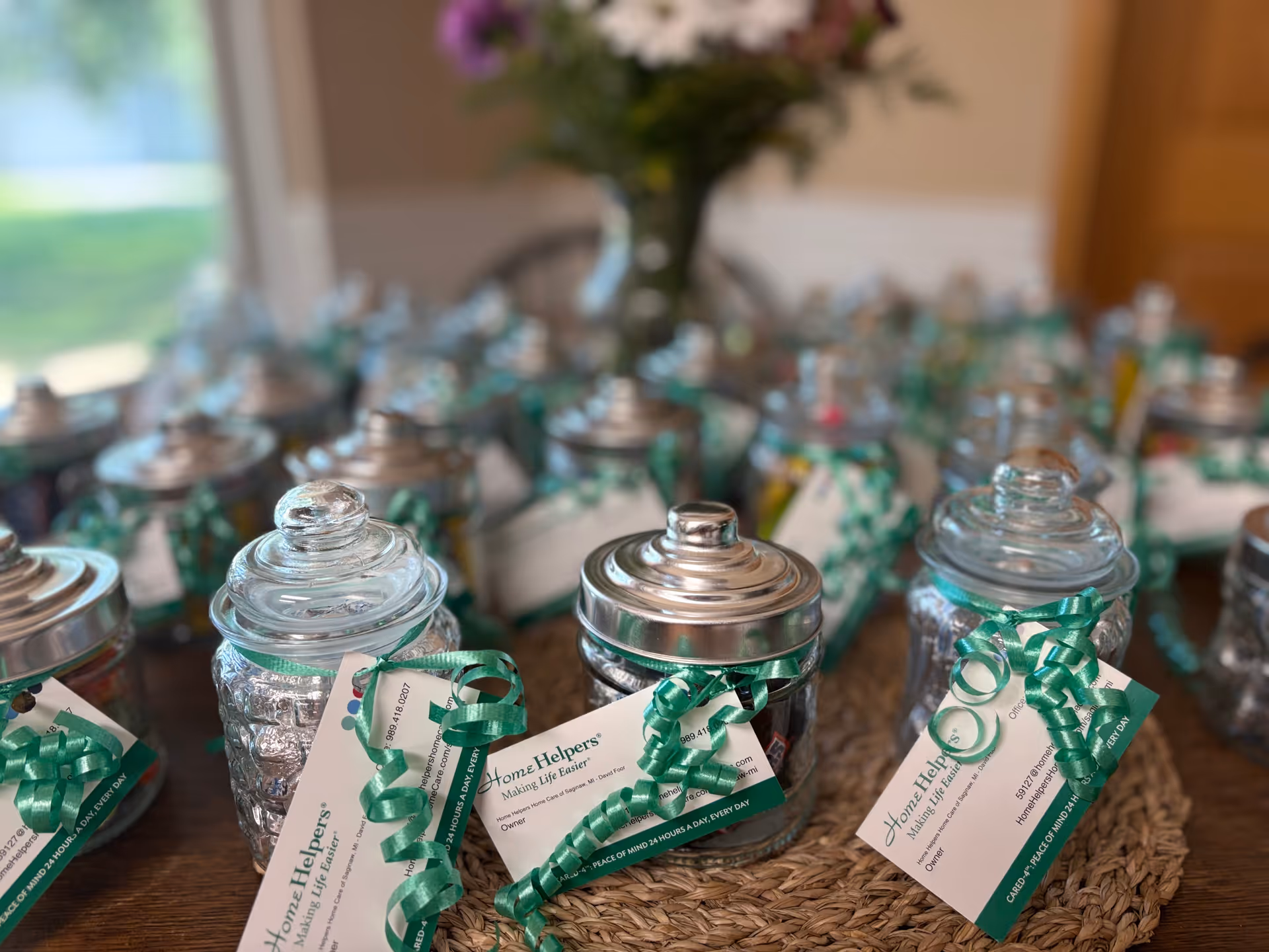 Row of glass jars with green ribbons and tags on a wooden table.