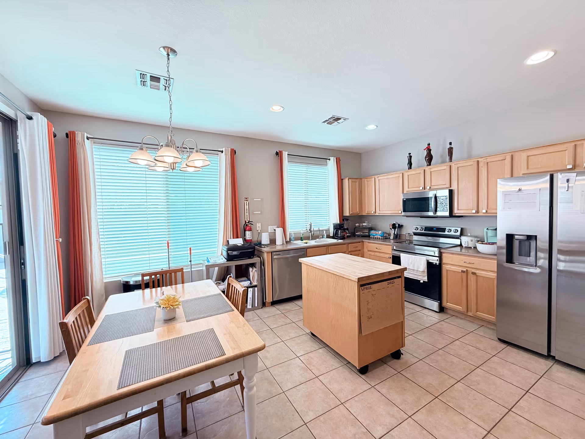 Bright kitchen with wooden cabinets, dining table, and stainless steel appliances.