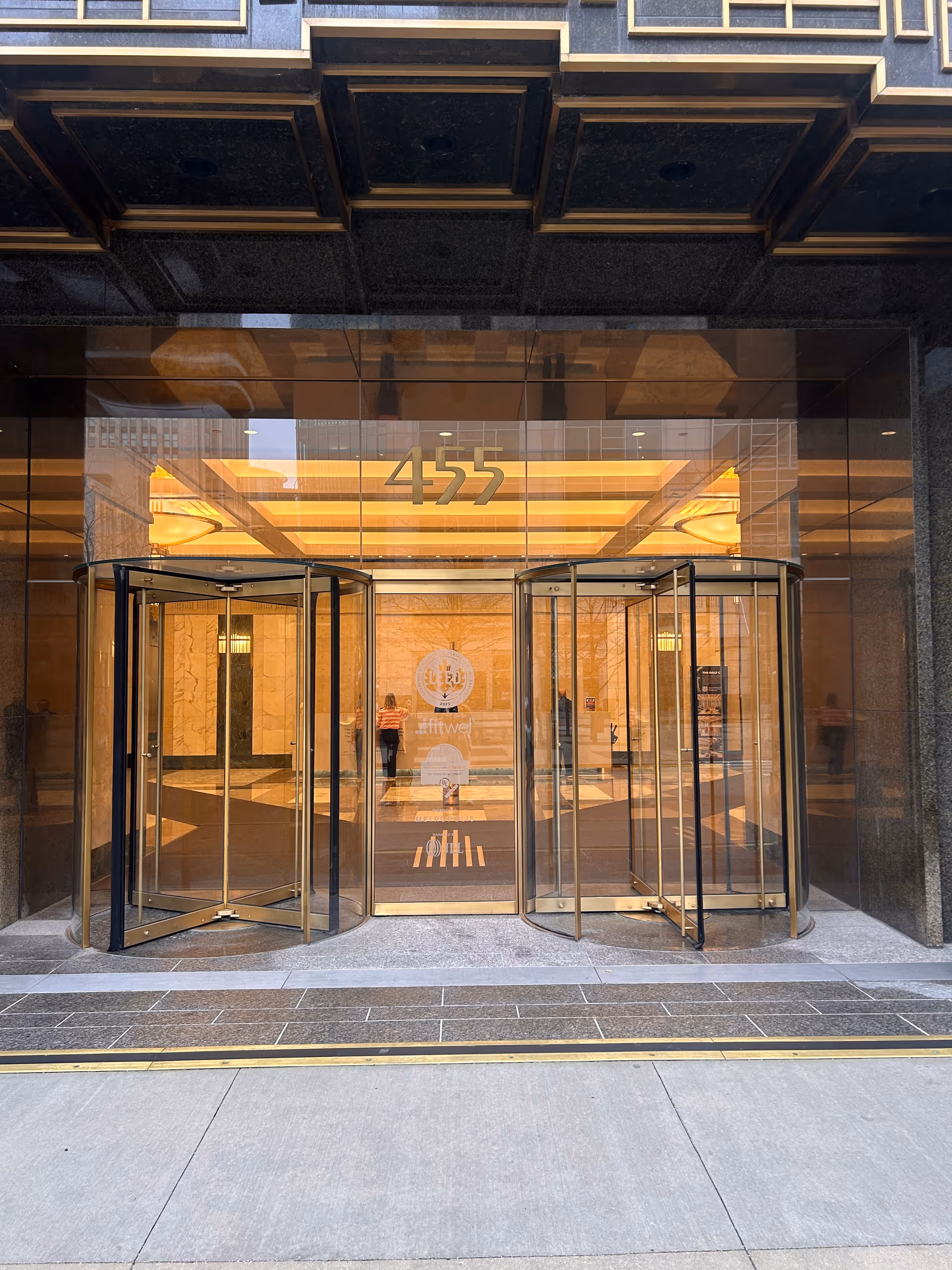 Glass revolving doors at the entrance of a tall building displaying the number 455