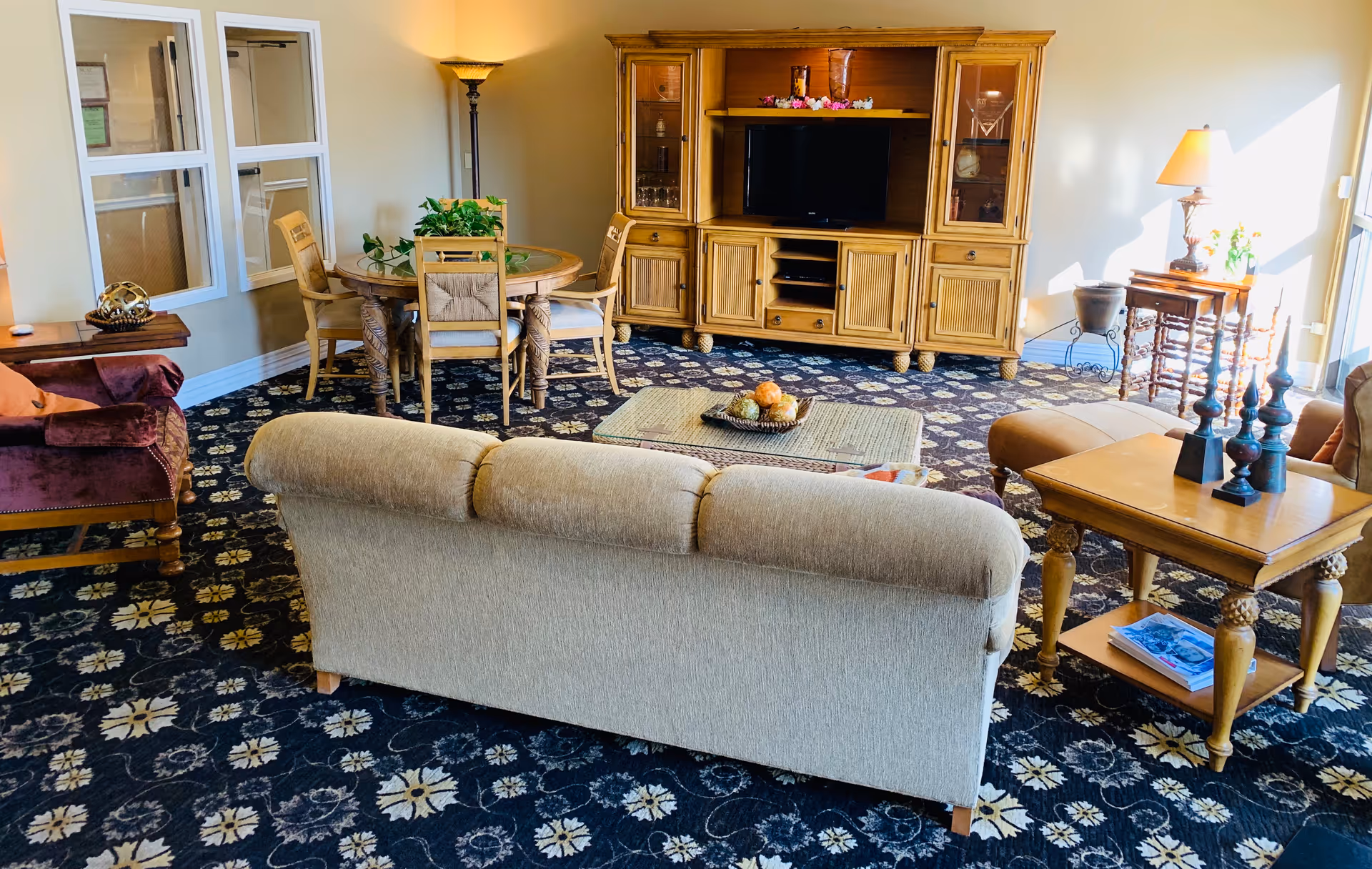 Cozy living room with beige sofa, wood entertainment center, and a round dining table.