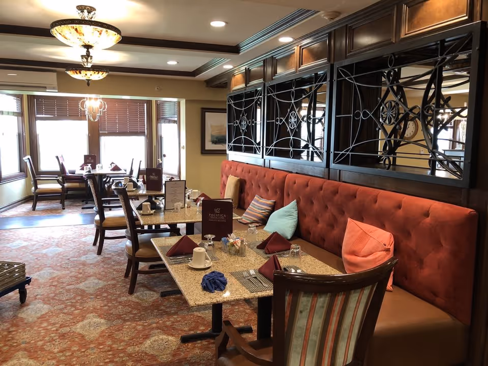 Cozy dining area with red tufted bench seating and tables set for meals.