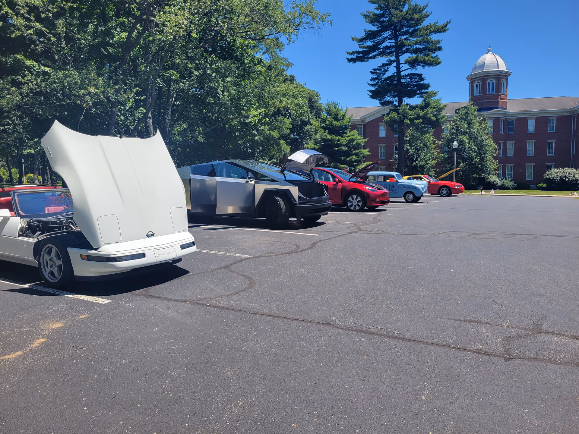 Wide parking lot in front of a brick building with a domed tower and trees.