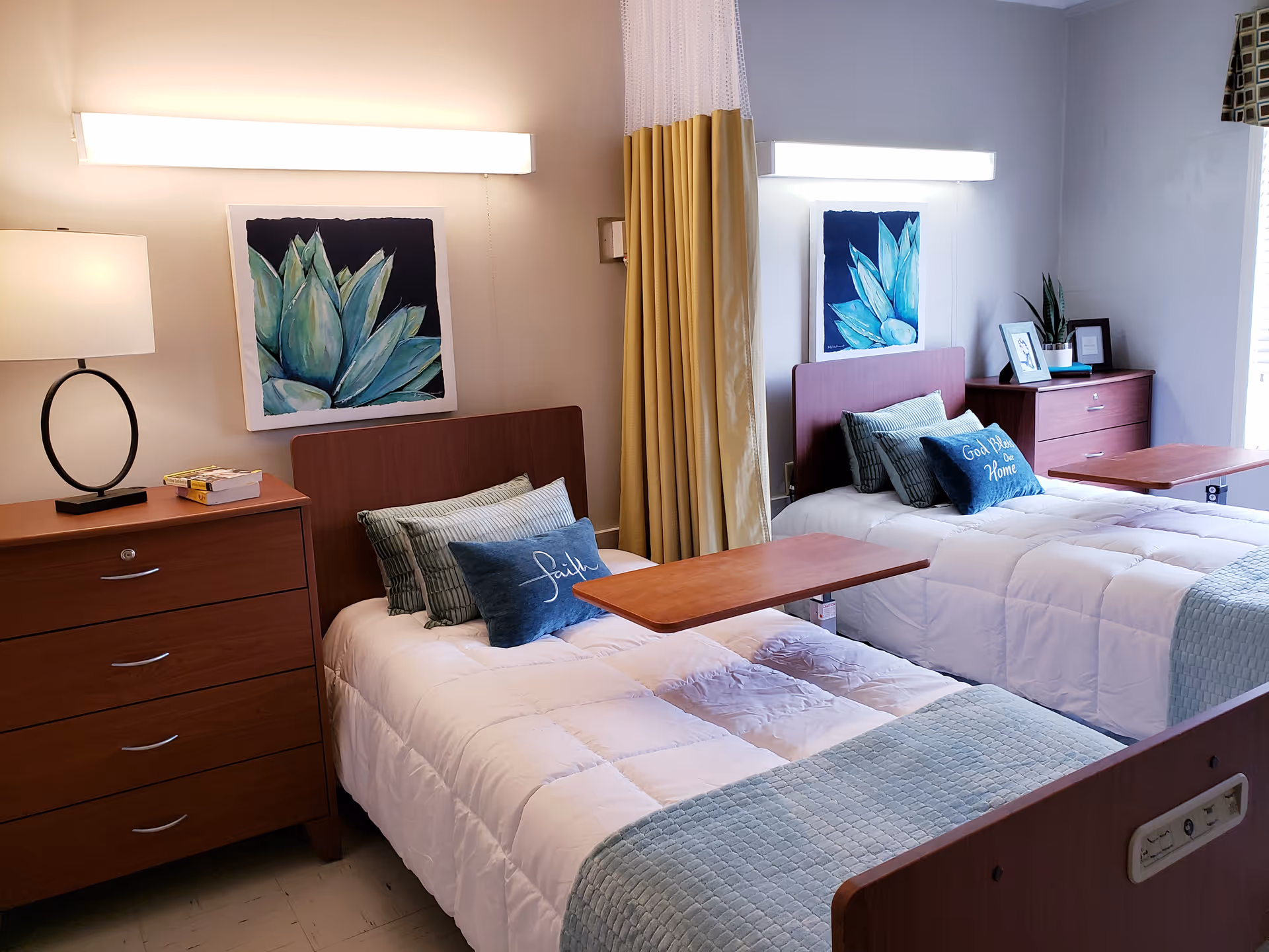 Two twin beds with white quilts, wooden dressers, and pastel decor in a shared hotel-style bedroom.