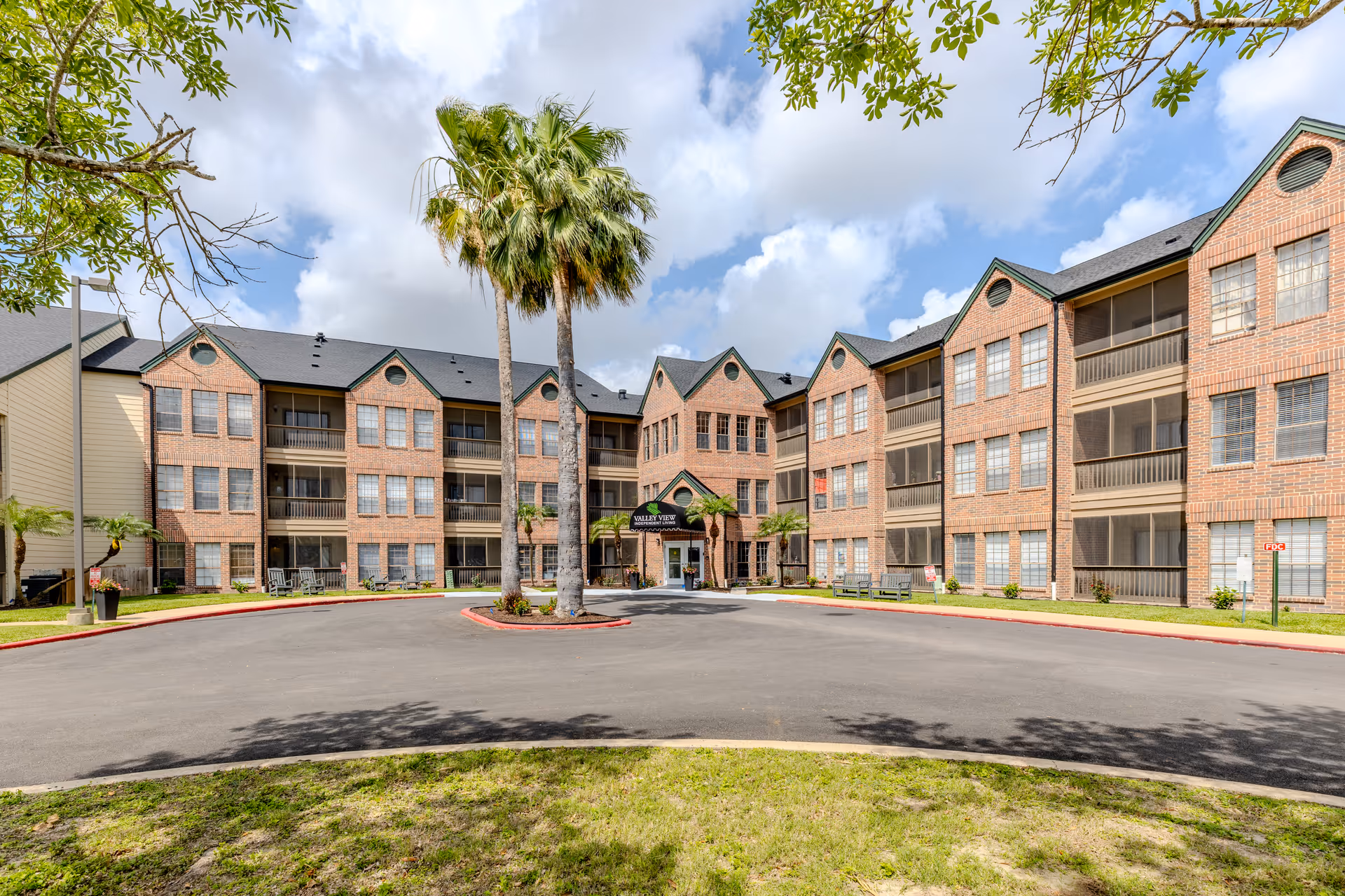 Brick multi-story senior living building with palm trees, a circular driveway, and a Valley View sign.