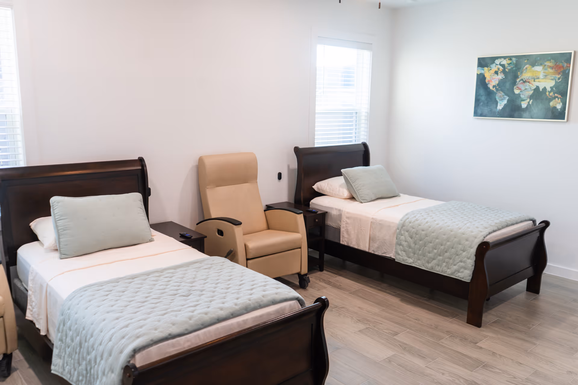 Two single beds with light blue quilts, a beige chair, in a shared bedroom.