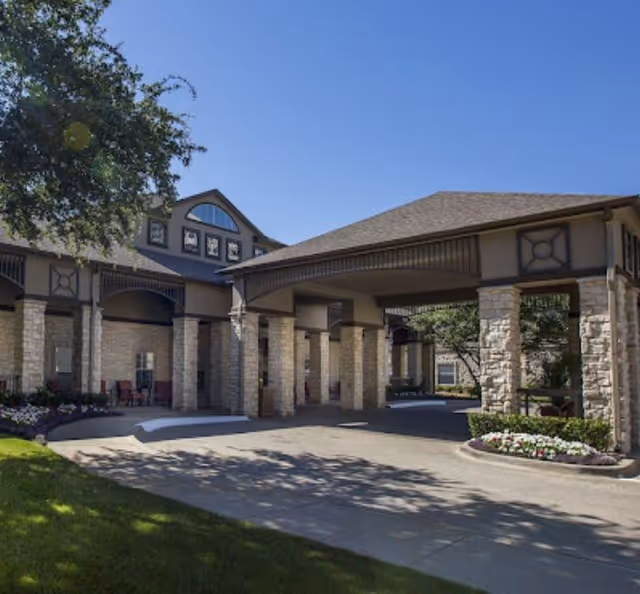 Front entrance of a senior living facility with stone columns and covered drive-through.