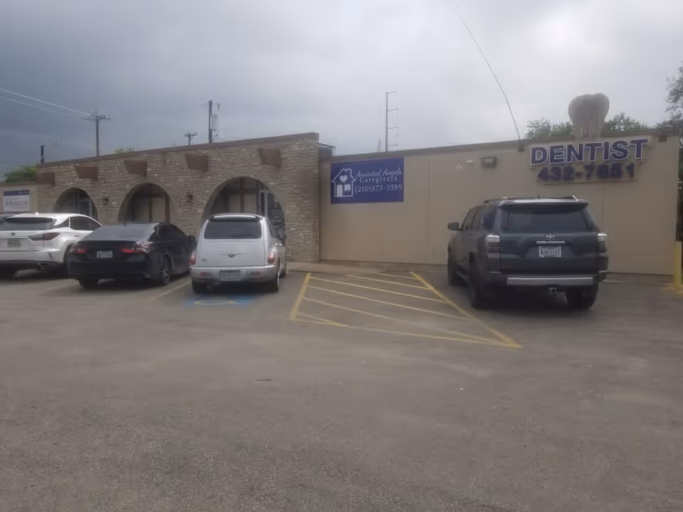Parking lot in front of beige building with a dentist sign and arched windows.