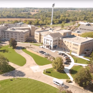 Aerial view of the Springfield Masonic Community campus showing a large multi-wing brick building with a circular driveway, parked vehicles, and surrounding lawns and trees.