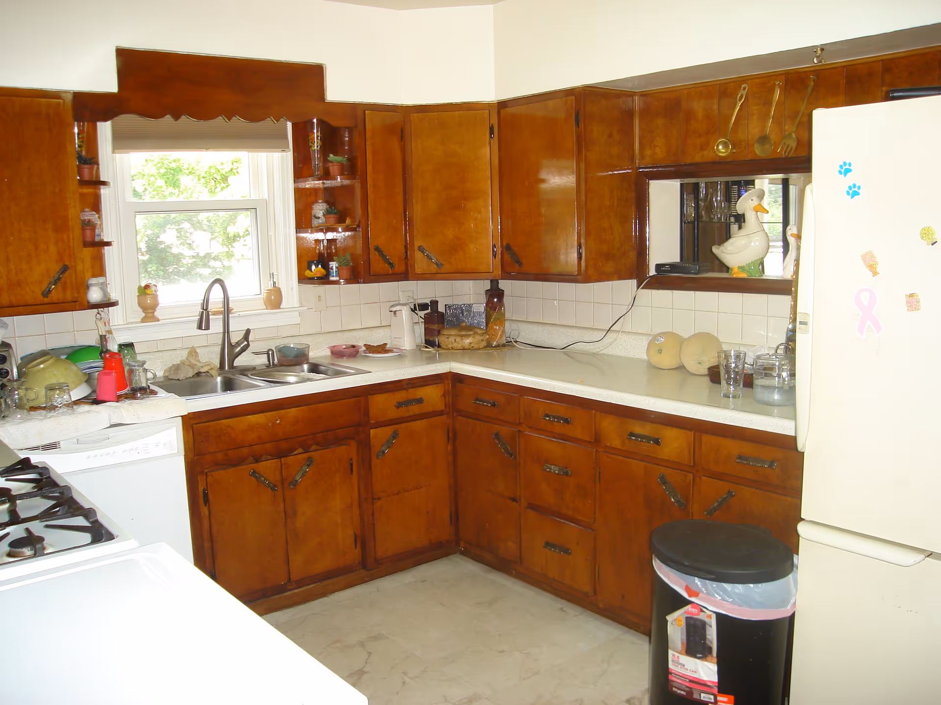 U-shaped kitchen with brown wooden cabinets, sink, stove, and refrigerator.