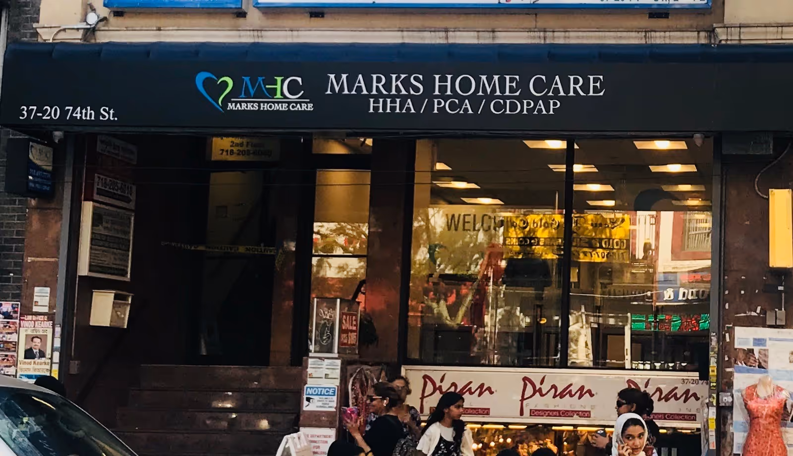 Storefront sign reads Marks Home Care Agency with pedestrians on the sidewalk.