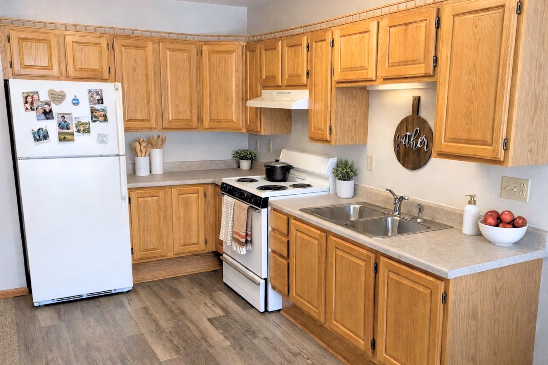 A clean Cardinal Grove kitchen with wooden cabinets, a refrigerator, stove, and double sink.