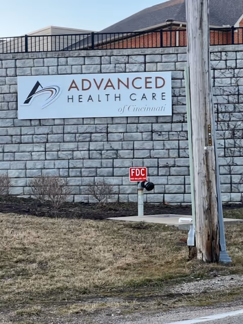 Exterior view of a stone wall with a sign reading Advanced Health Care of Cincinnati.