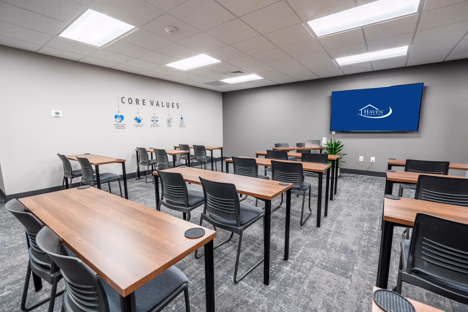 Training room with multiple wooden desks, black chairs, and a Haven display on the wall.