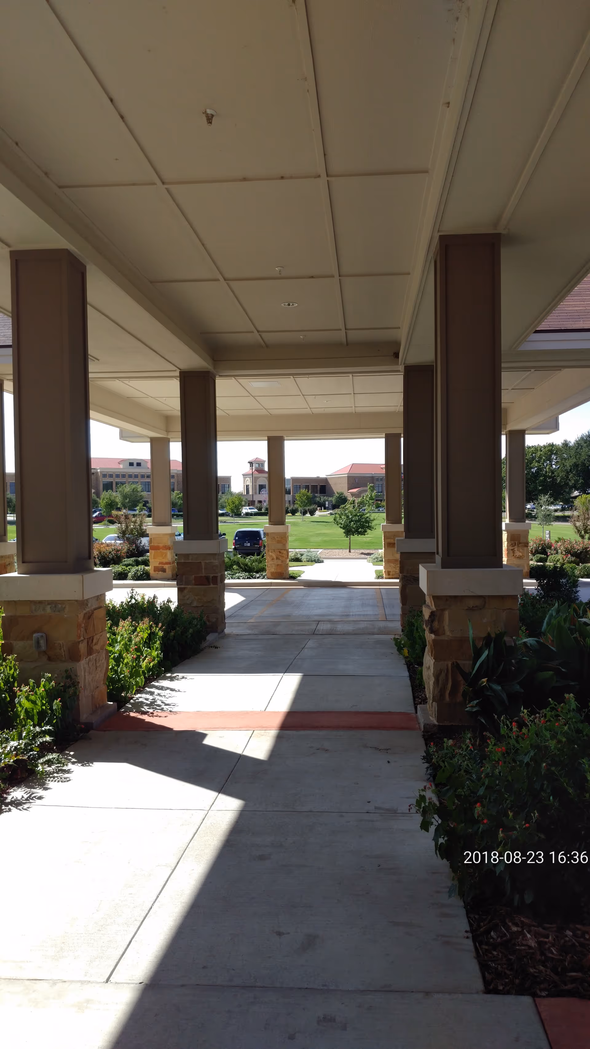 Covered exterior walkway entrance of Hendrick Hospice Care campus with columns and landscaping.