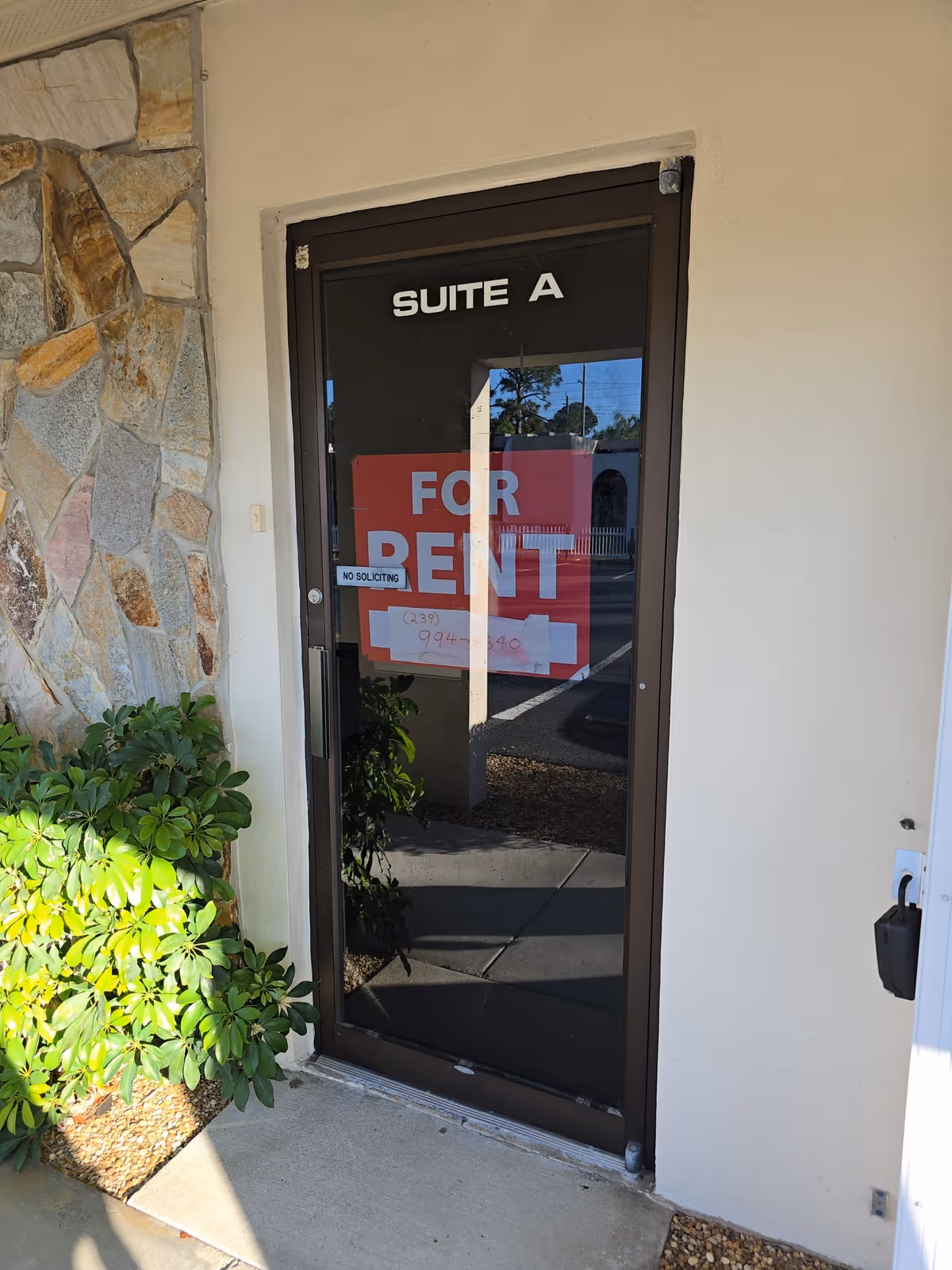 Door labeled Suite A with a large red FOR RENT sign visible through glass.