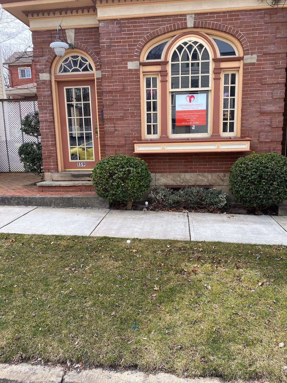 Brick building with arched windows and a Compassionate Hearts sign in the window.