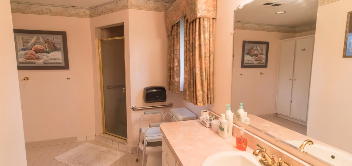 Facility bathroom with sink, mirror, shower, and countertop space.