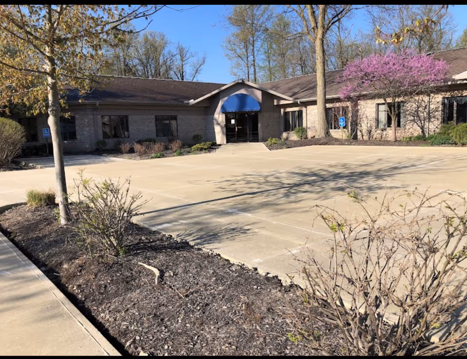 Exterior view of a single-story senior care facility with a blue awning and parking lot