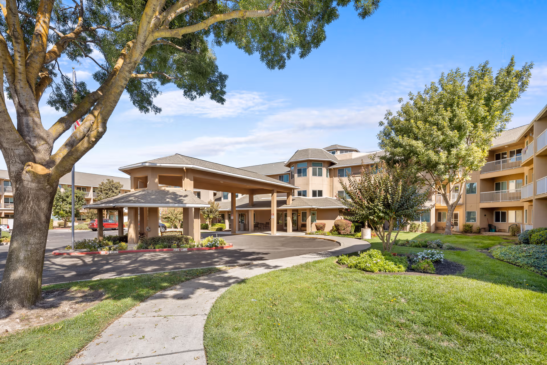 Exterior view of The Hampshire senior living facility with a circular driveway and landscaped grounds.