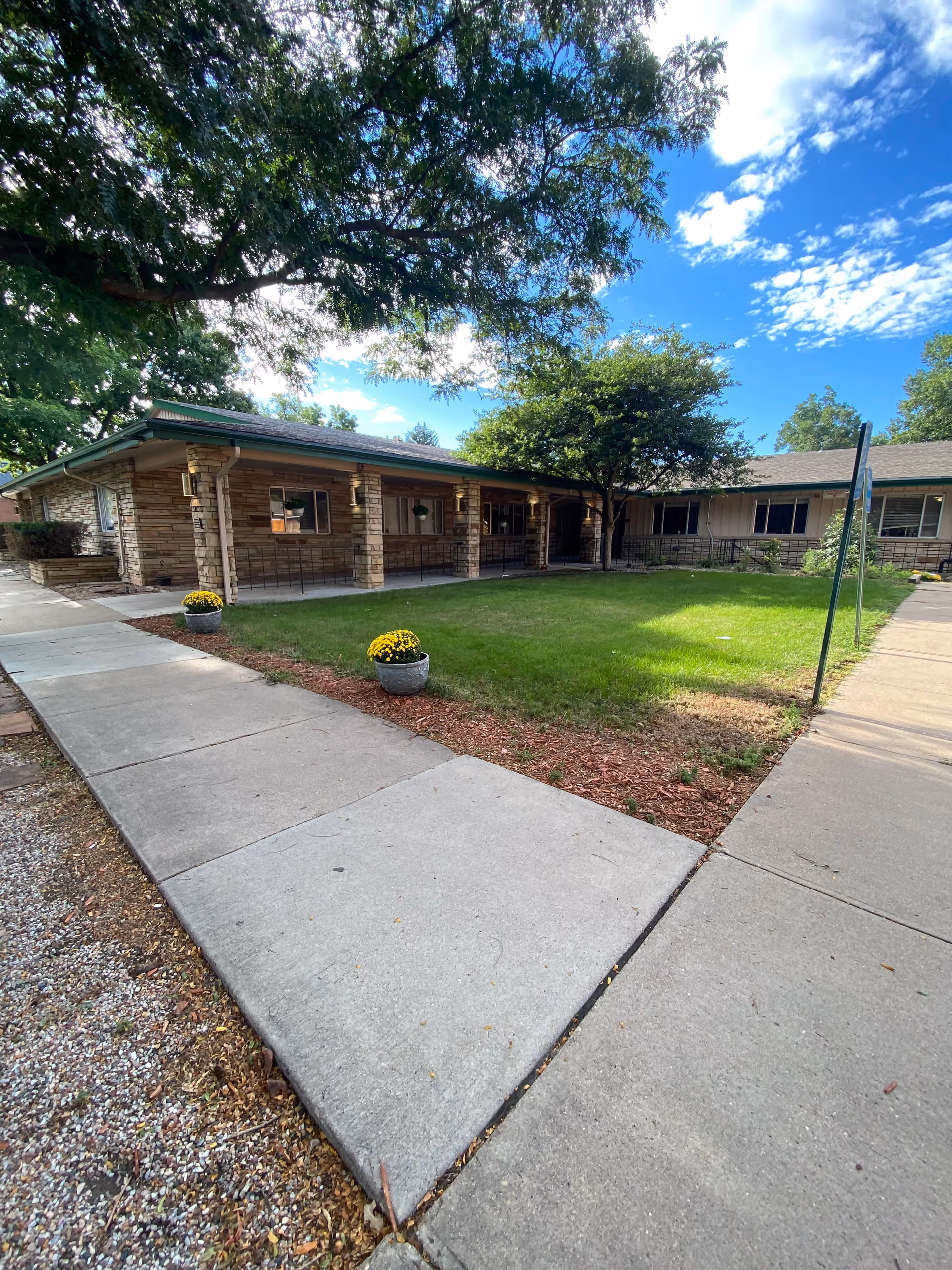 Single-story Prestige Care Center exterior with stone columns, lawn, and walkway.