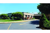 Front exterior view of Brookhaven Health Care Facility with landscaped shrubs and driveway.