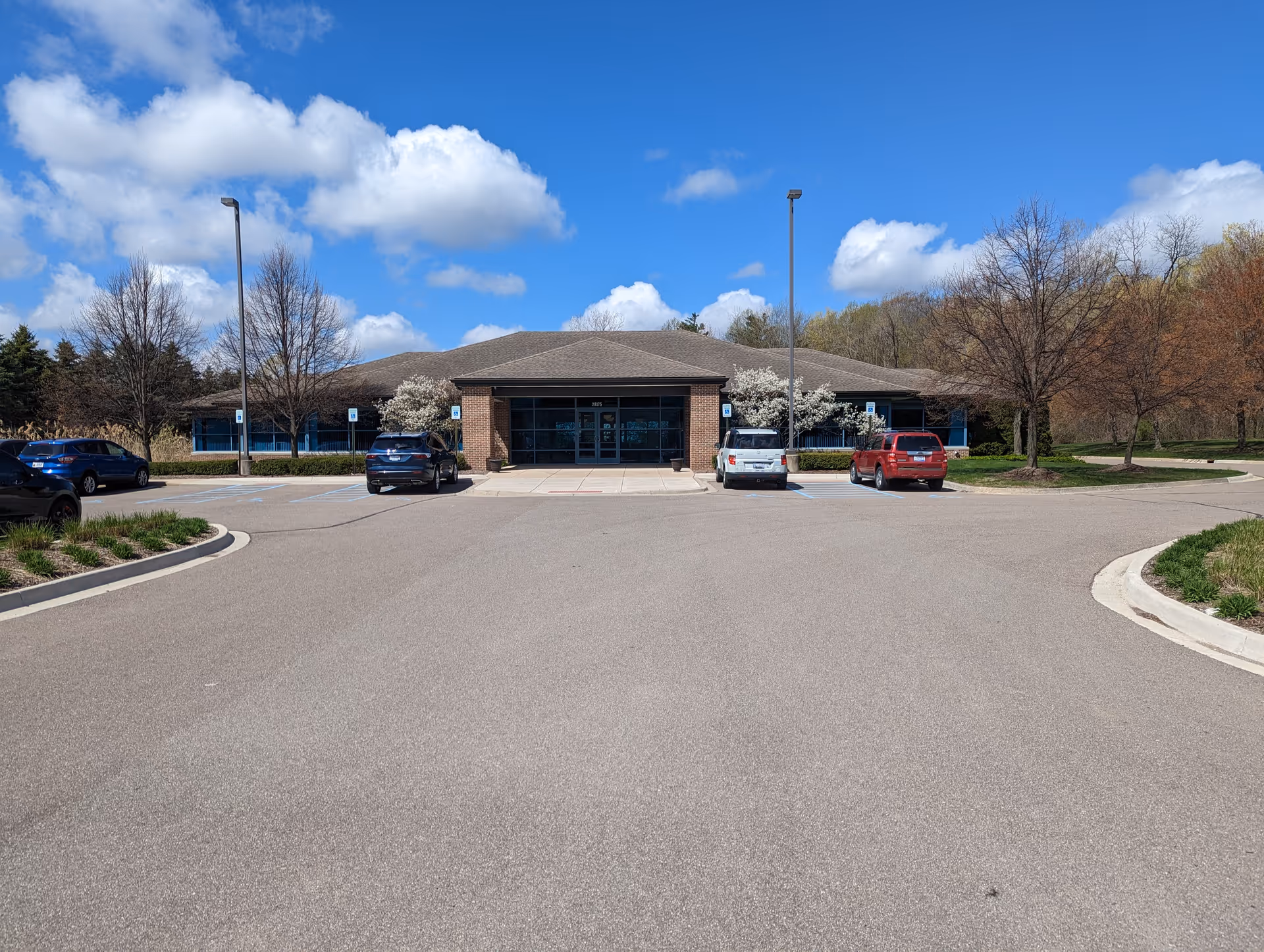 Front view of a brick senior care center entrance with glass doors and surrounding parking lot.
