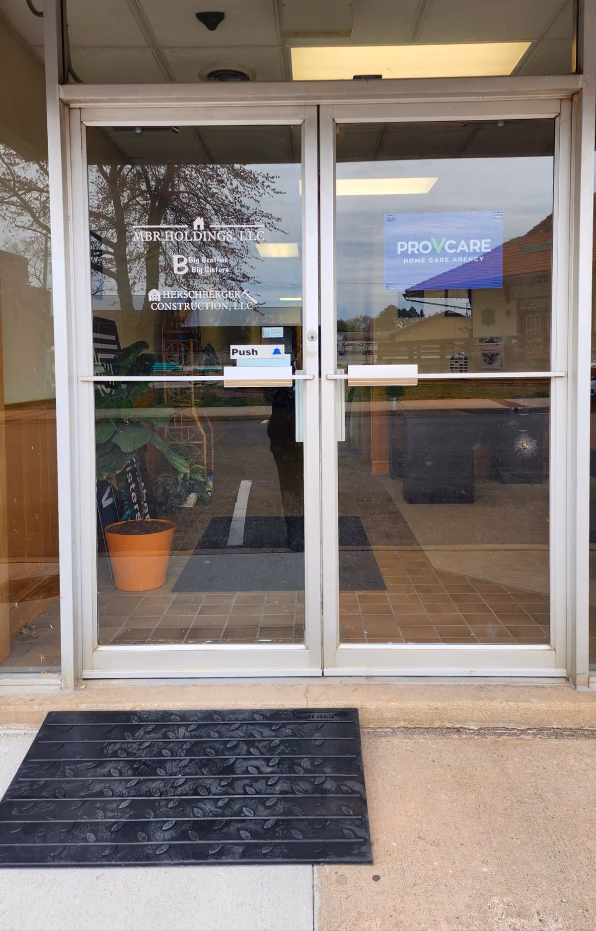Glass double doors labeled ProVcare Home Care Agency at the entrance, with ramp outside.
