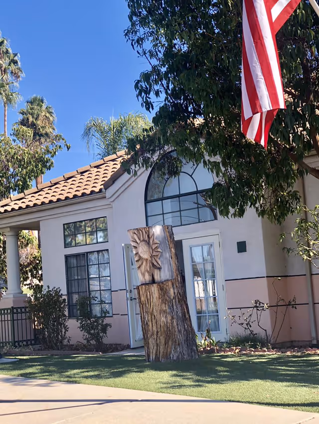 Exterior view of Oak Hill Residential Care building with flag, arched window, and wooden sculpture.