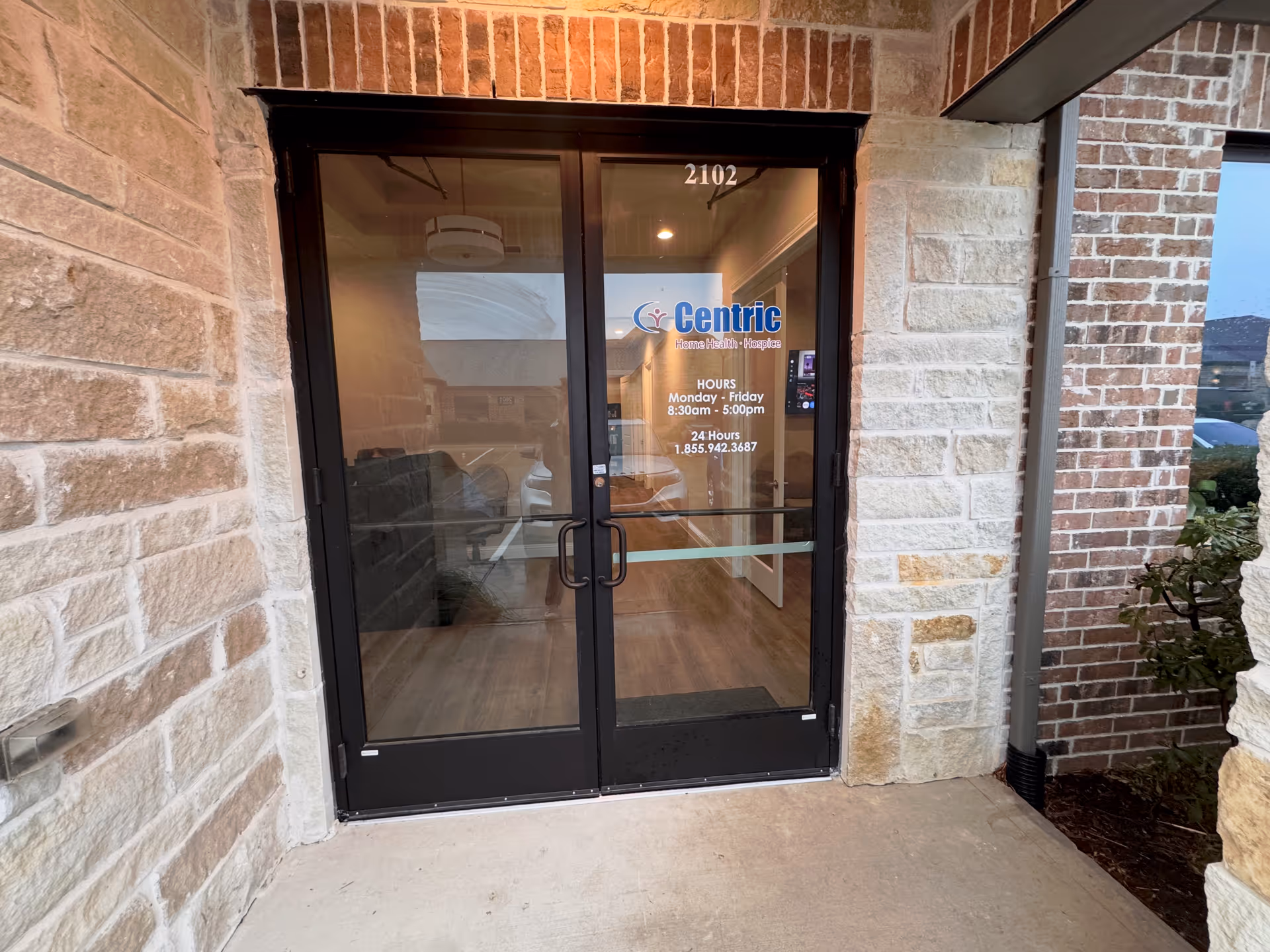 Exterior entrance of Centric Home Health and Hospice with glass doors and brick facade