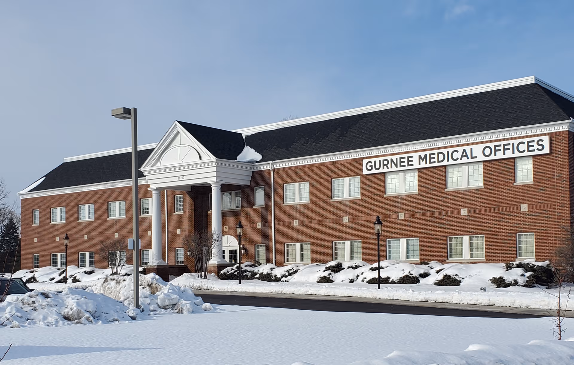 Two-story brick medical building with a portico and a snow-covered parking lot.