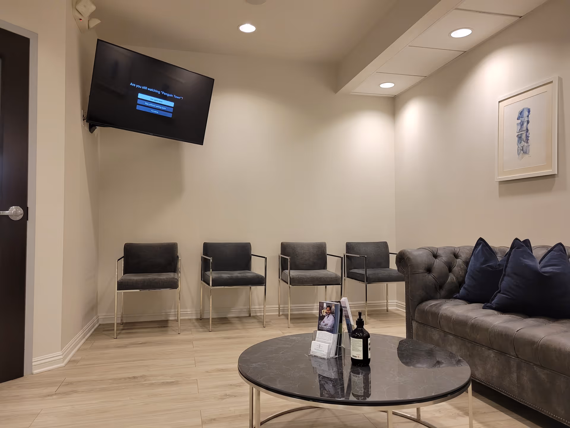 Modern waiting area with chairs along the wall, a gray sofa, and a round coffee table.