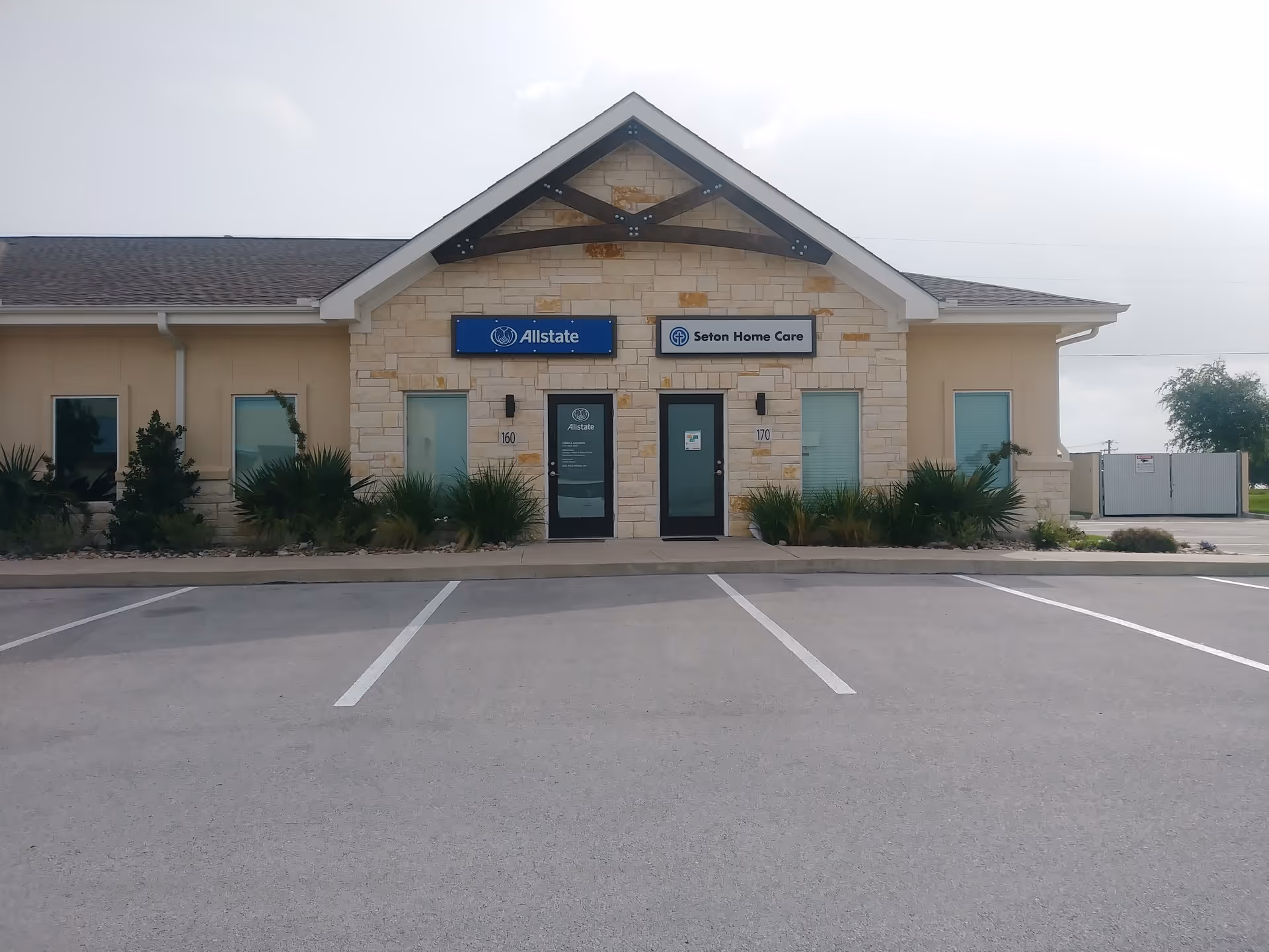 Front view of a beige stone facility with Allstate and Seton Home Care signs.