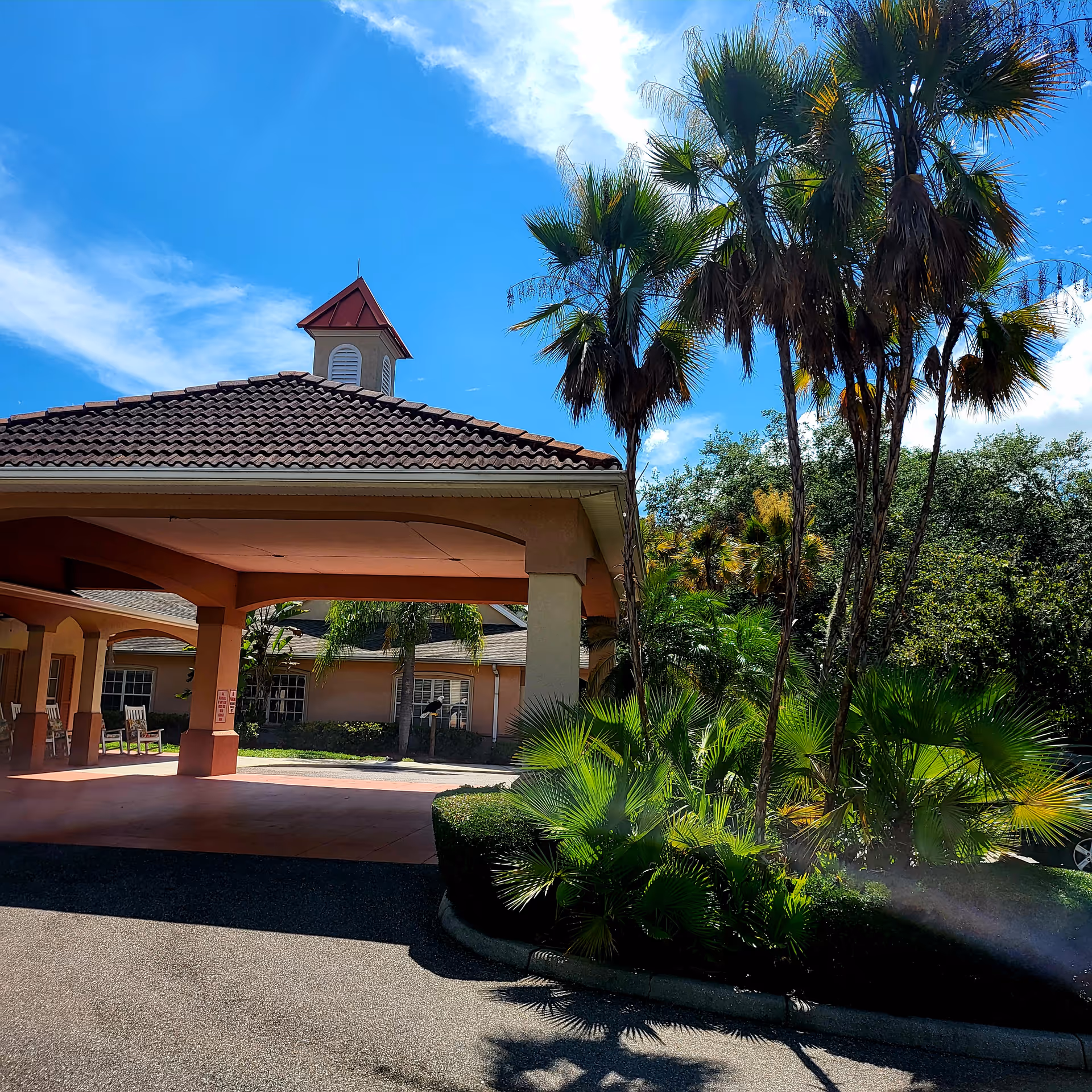 Entrance at Hawthorne Inn of Brandon with palm trees and tiled roof.