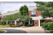Exterior view of Serenity at Cedar Park Assisted Living building with trees and driveway.