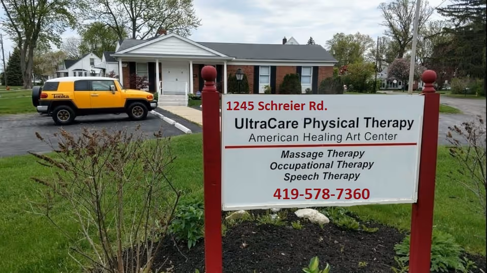 Outdoor scene with a sign for UltraCare Physical Therapy near a brick building and yellow vehicle.