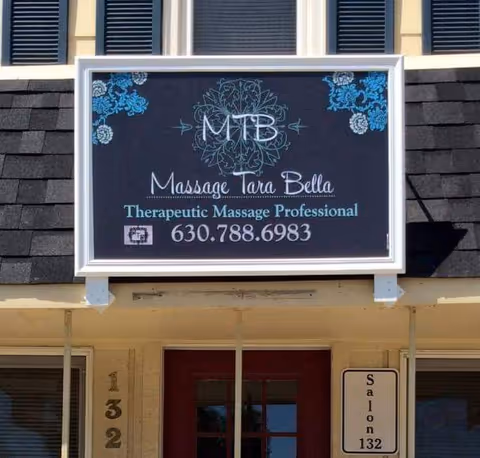Signboard reading Massage Tara Bella Therapeutic Massage Professional above storefront entrance.