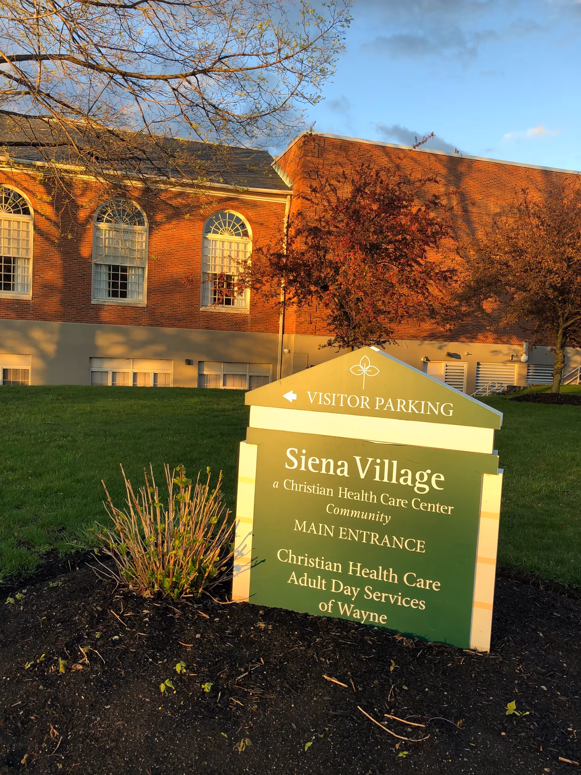 Brick building exterior with a Siena Village sign and landscaped lawn.