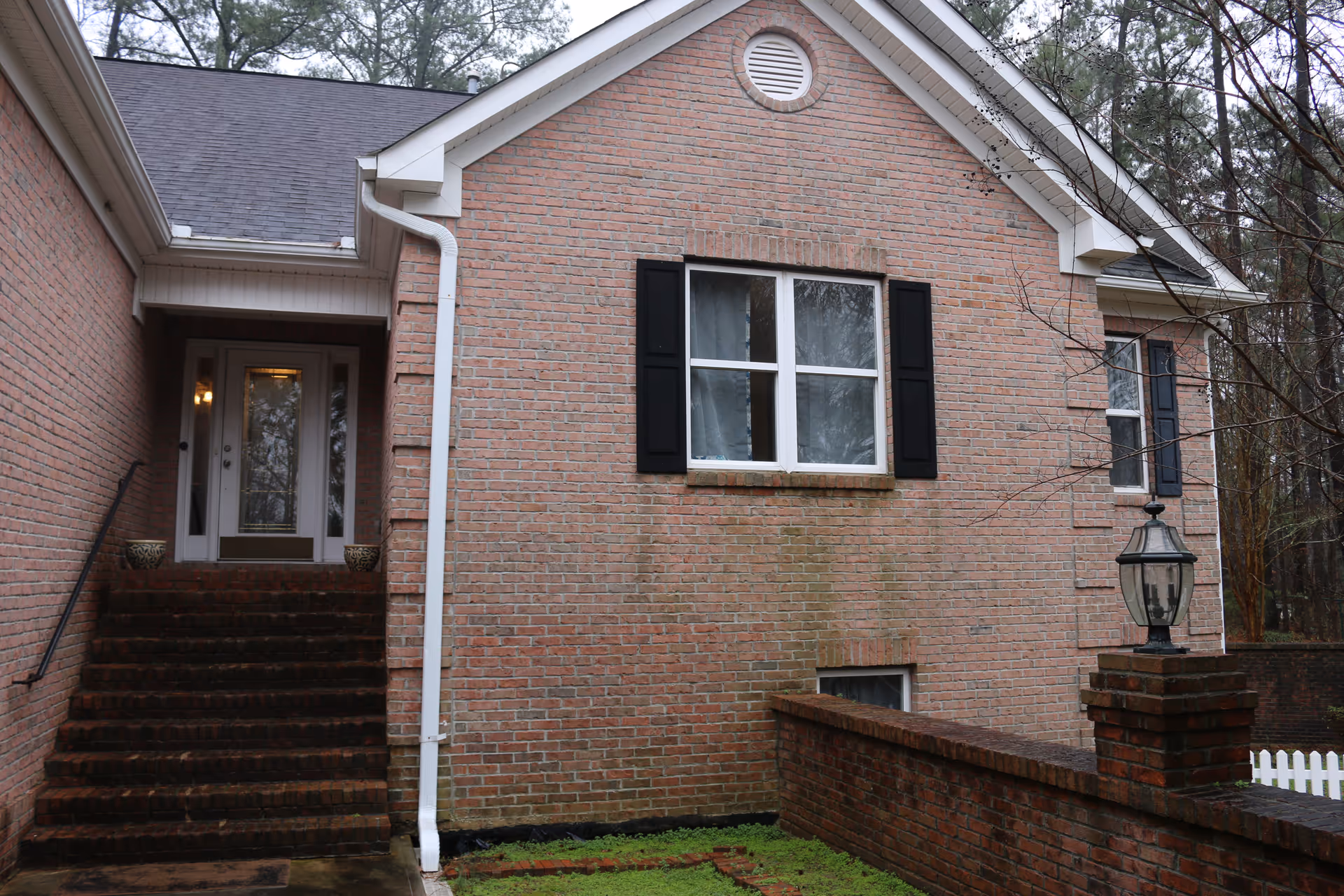 Brick facility exterior with front entrance, stairs, and a windowed facade.