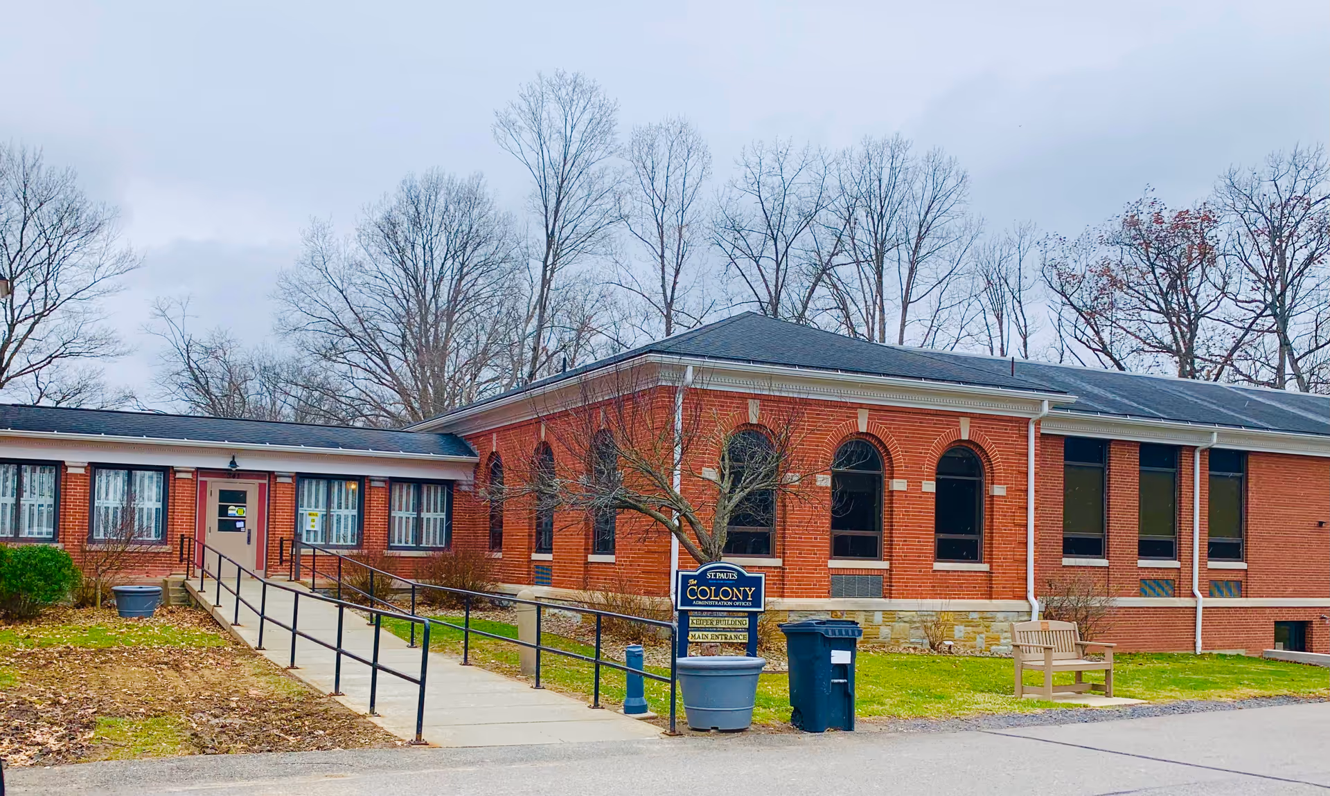 Brick senior living facility exterior with ramp and bench