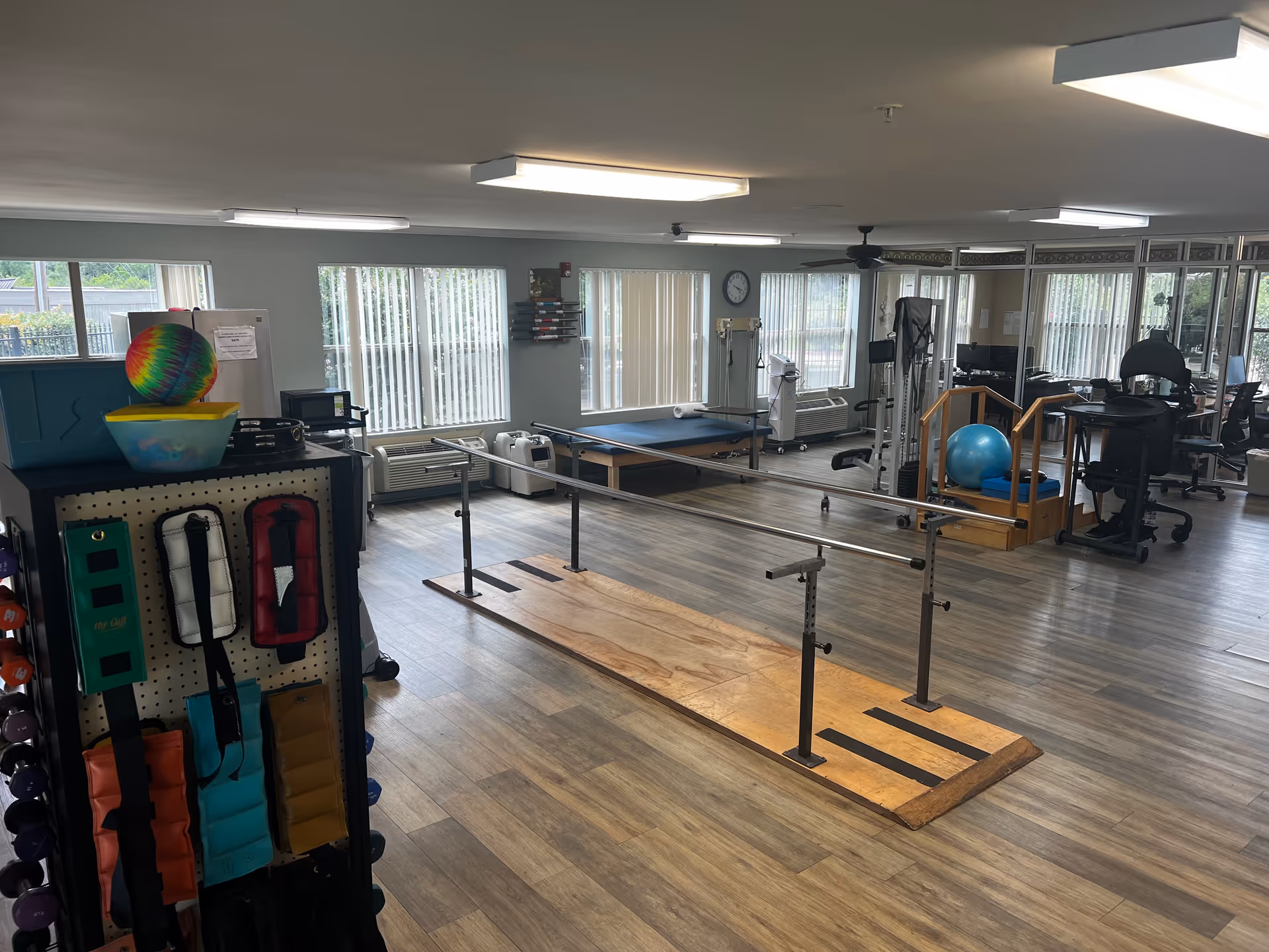 Interior rehab gym with parallel bars, exercise equipment, and large windows