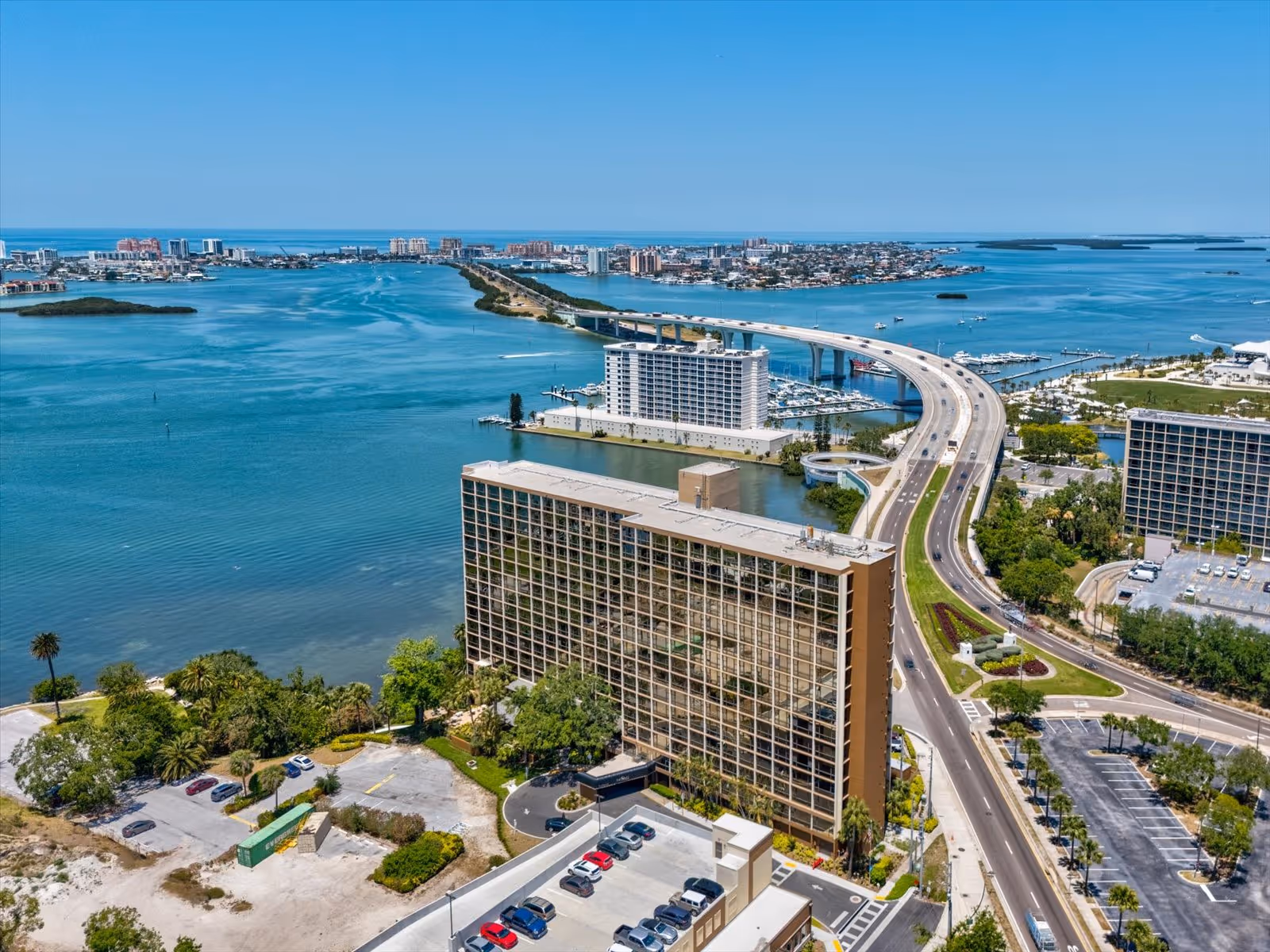 Aerial view of waterfront high-rise buildings, a bridge, and blue water.