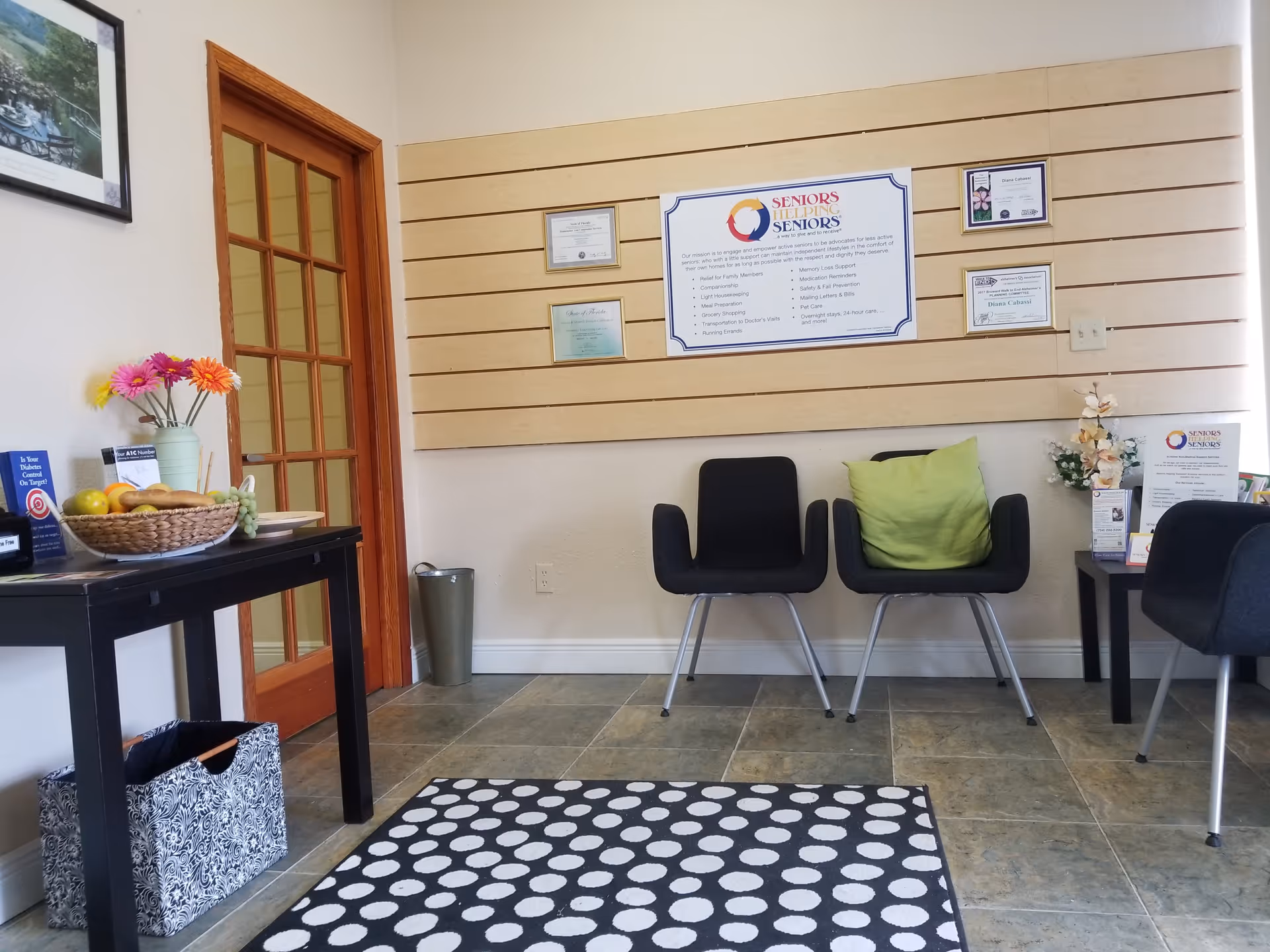 Interior lobby featuring black chairs, wall displays, a doorway, and a patterned rug.