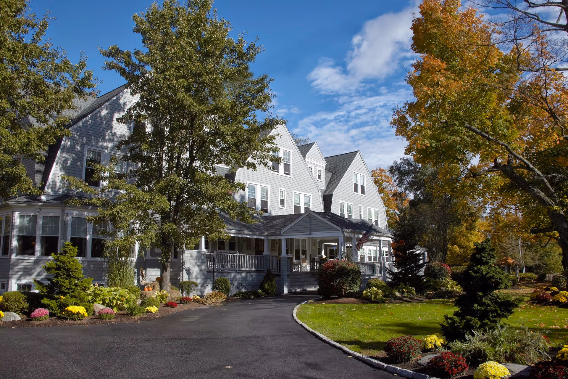 A grey, multi-story Sunrise of Weston senior living building with a front porch and landscaped grounds.