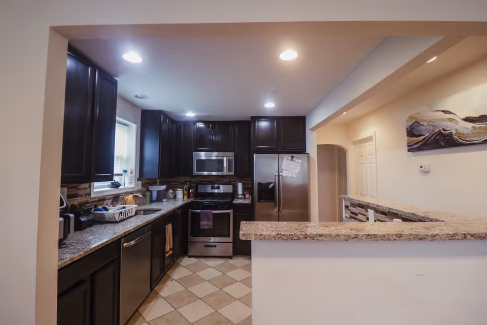 Modern kitchen with dark cabinets, granite counters, stainless appliances, and a raised breakfast bar.